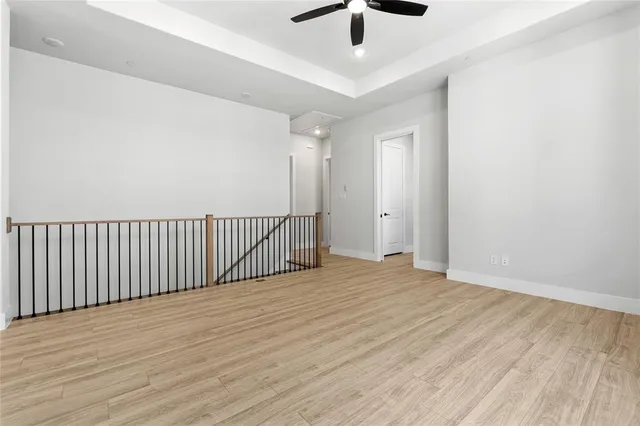 an empty room with wooden floor chandelier fan and windows