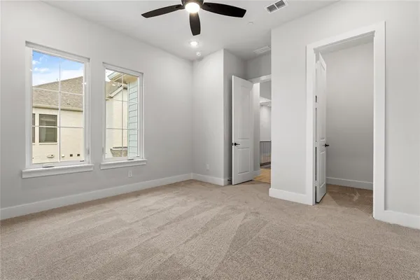 an empty room with chandelier fan and windows