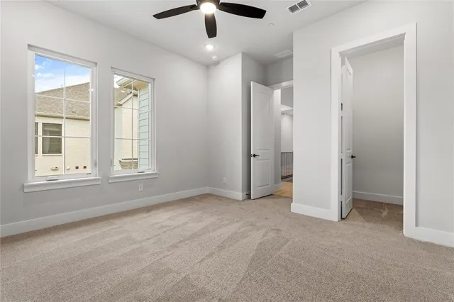 an empty room with chandelier fan and windows
