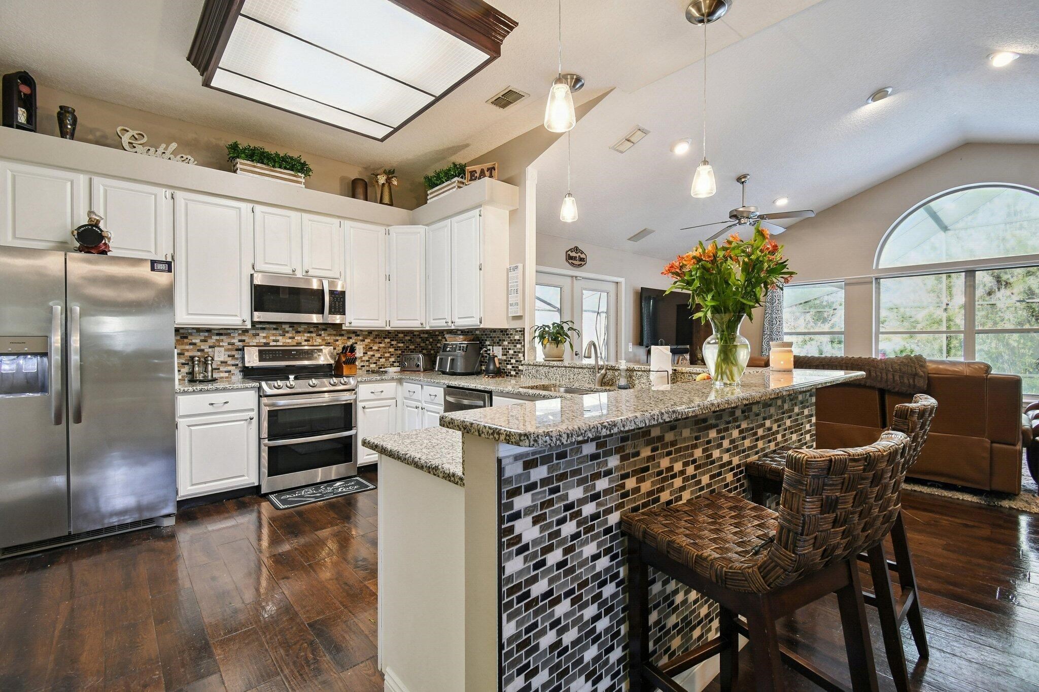 1220 Creek Bend Road Jacksonville, FL 32259 - Photo 9 of 30 Kitchen with stainless steel appliances, white cabinets, decorative light fixtures, light stone counters, and vaulted ceiling