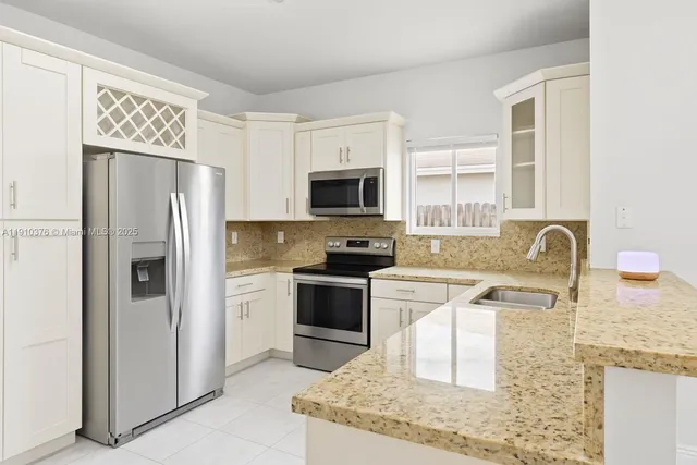 a kitchen with stainless steel appliances granite countertop a refrigerator stove microwave and sink