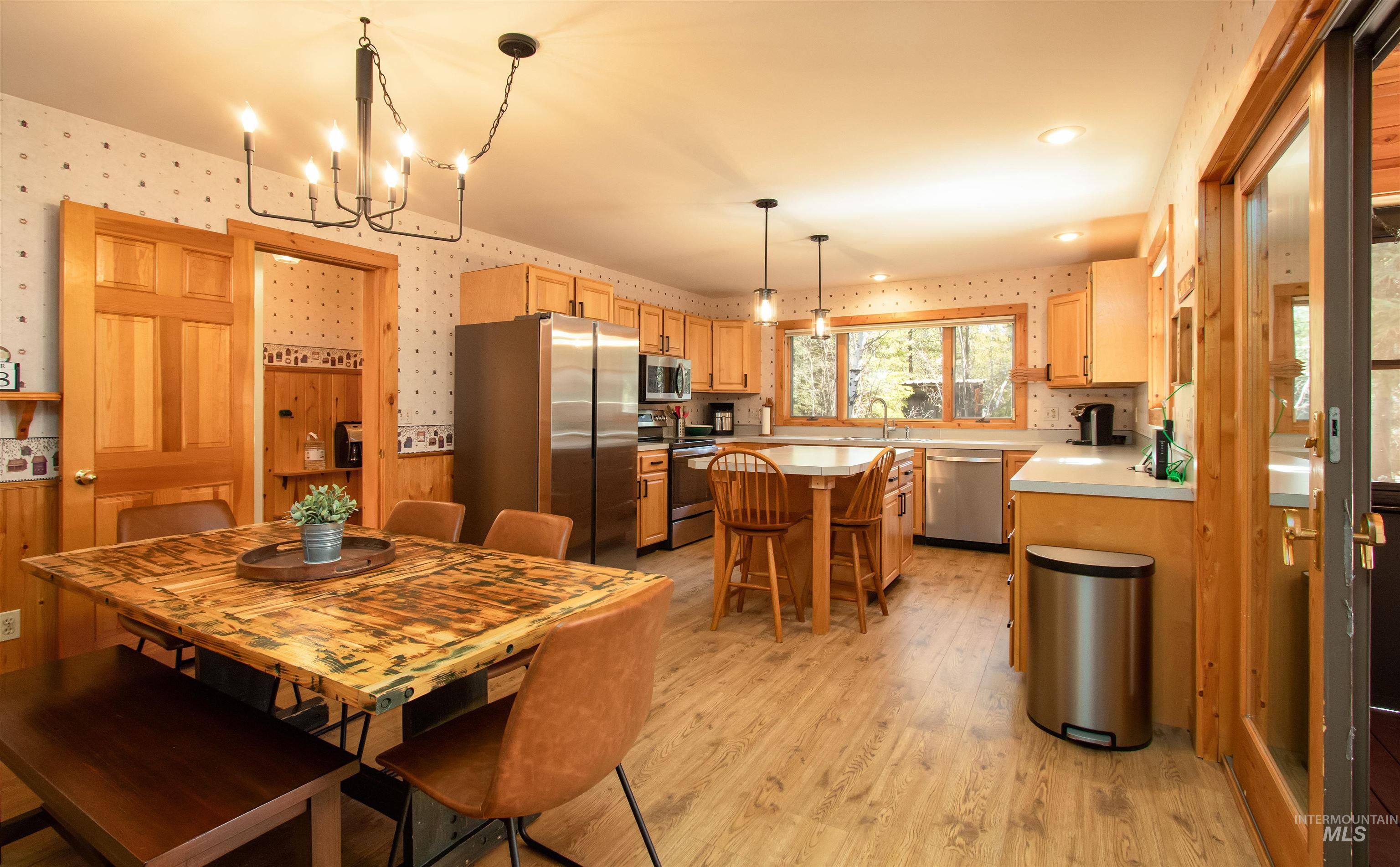 12712 Hereford Road Donnelly, ID 83615 - Photo 13 of 50 Dining area featuring wallpapered walls, light wood-style floors, hanging lights, and wainscoting