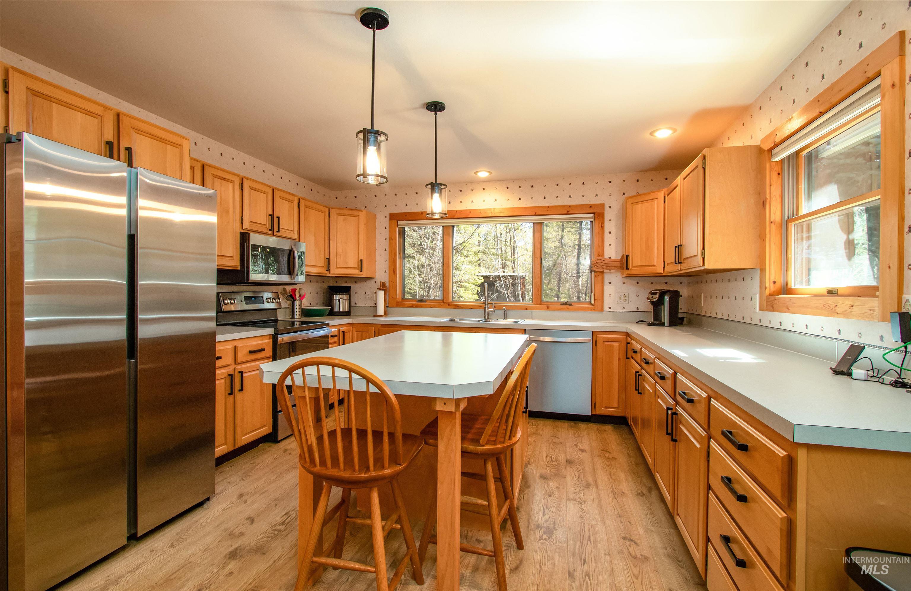 12712 Hereford Road Donnelly, ID 83615 - Photo 15 of 50 Kitchen with stainless steel appliances, light countertops, light wood-style flooring, a kitchen breakfast bar, and wallpapered walls
