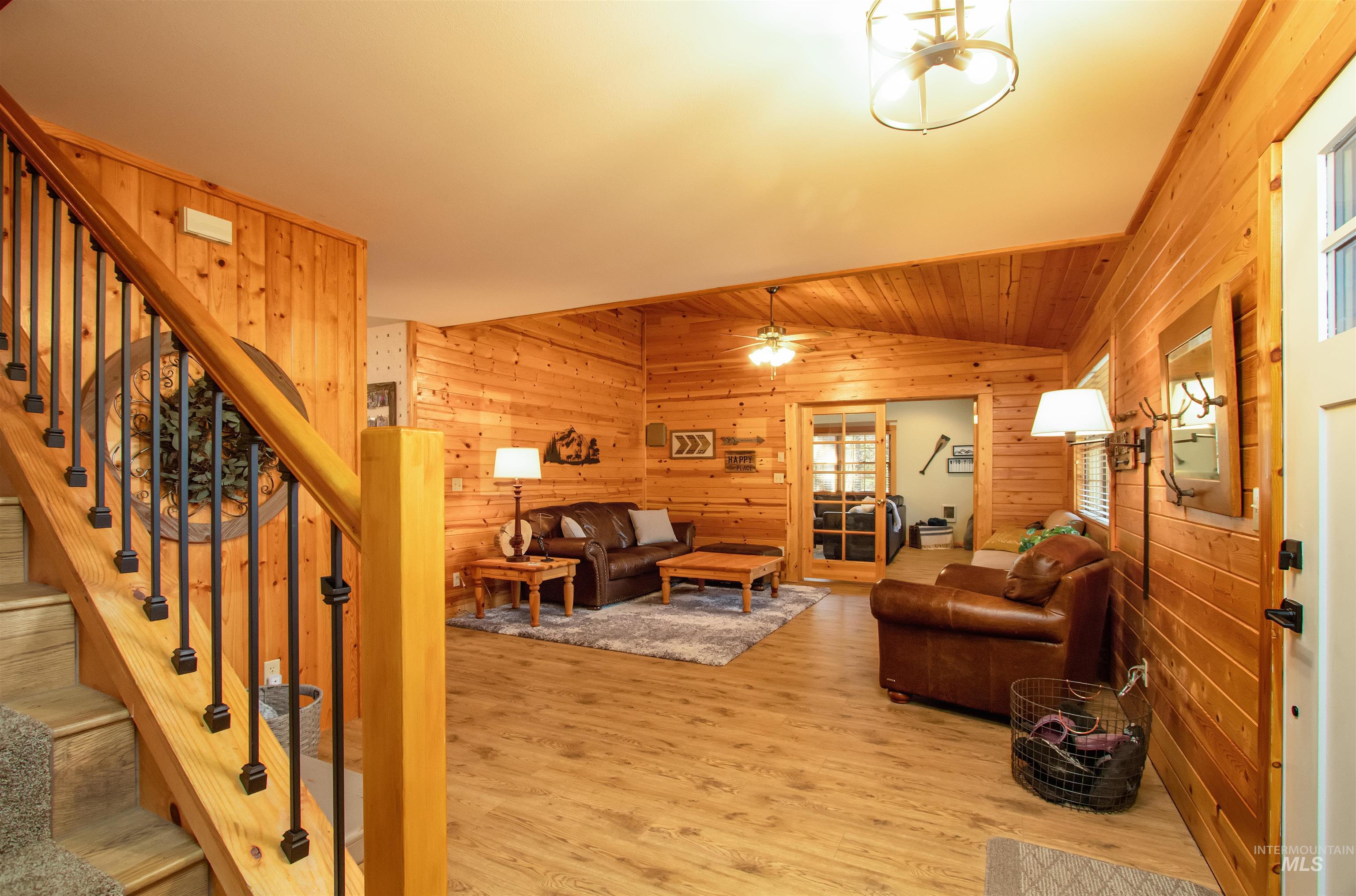12712 Hereford Road Donnelly, ID 83615 - Photo 18 of 50 Living room featuring lofted ceiling, wood walls, wood finished floors, and a ceiling fan