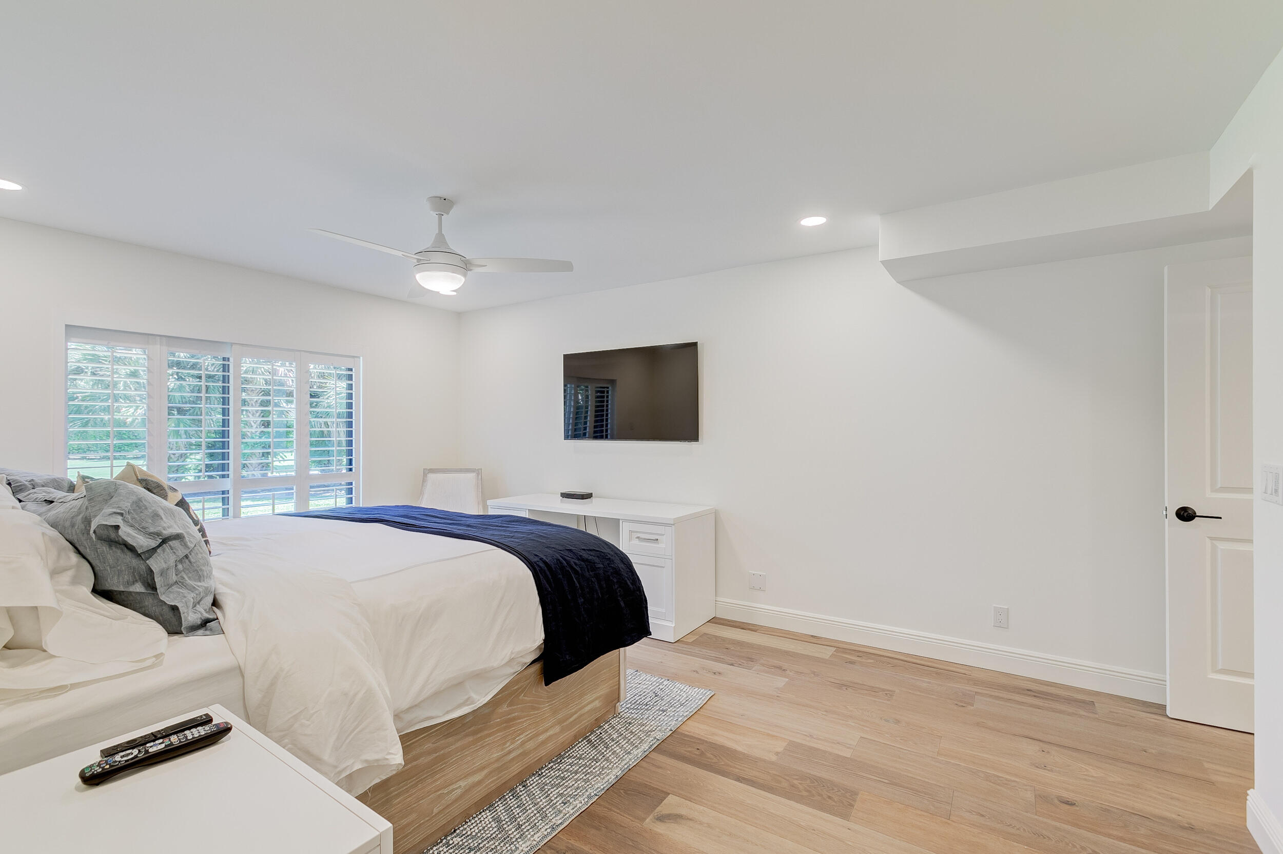 16622 Traders Crossing North, Unit 102 Jupiter, FL 33477 - Photo 11 of 19 a bed room with a bed a television and a large window