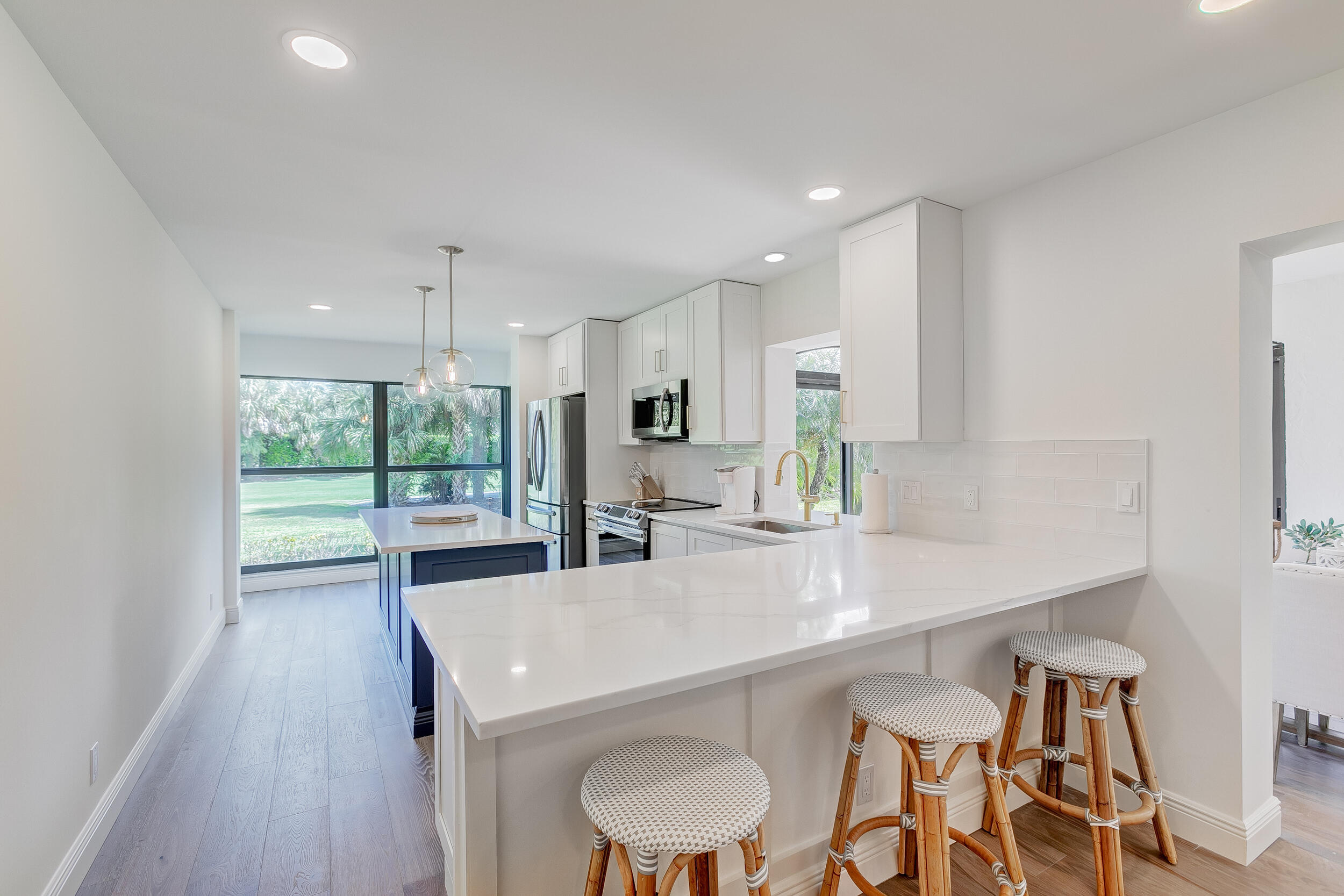 16622 Traders Crossing North, Unit 102 Jupiter, FL 33477 - Photo 7 of 19 a kitchen with a table chairs refrigerator and microwave