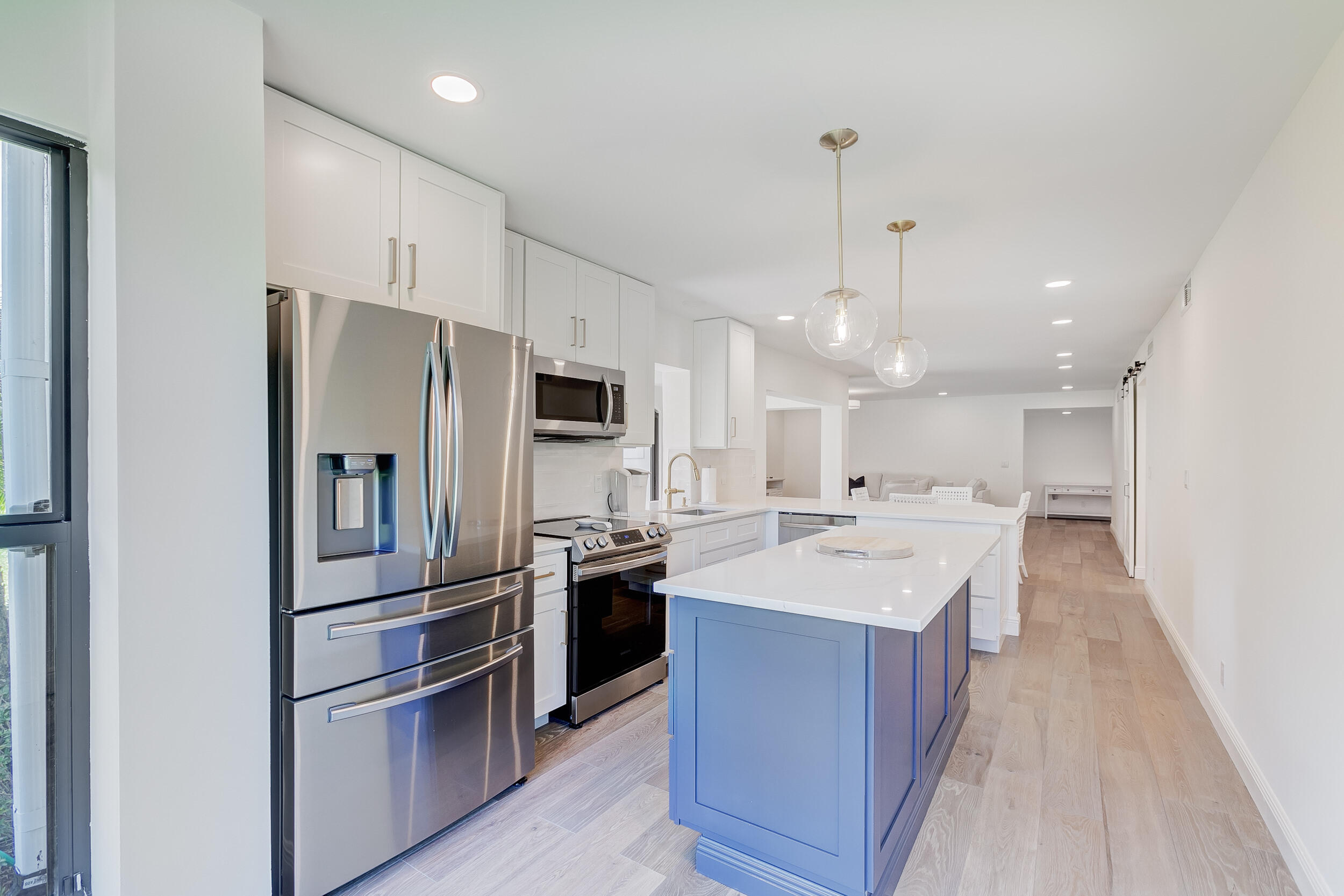 16622 Traders Crossing North, Unit 102 Jupiter, FL 33477 - Photo 9 of 19 a large kitchen with stainless steel appliances kitchen island granite countertop a refrigerator and a sink