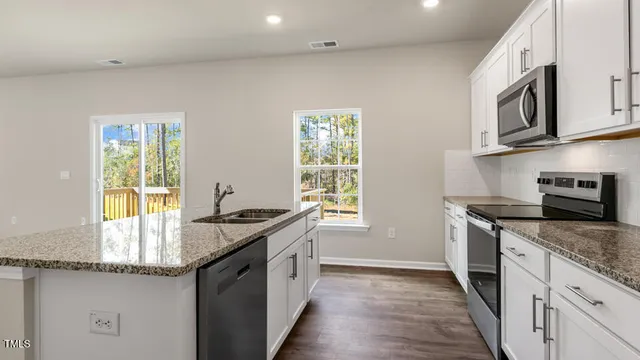 a kitchen with stainless steel appliances granite countertop a sink stove and microwave