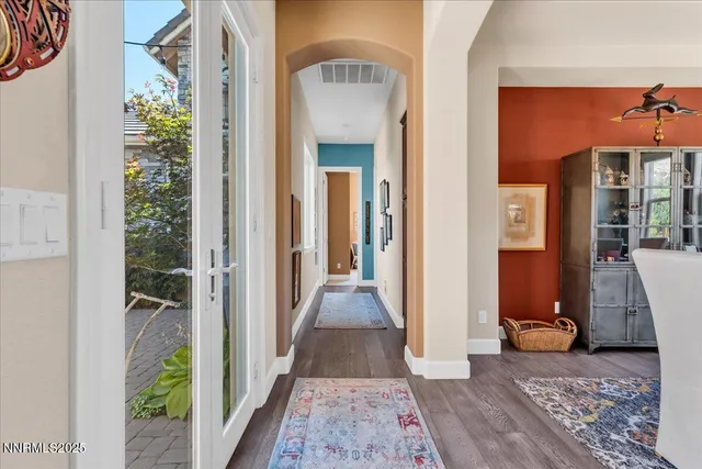 a view of a hallway with wooden floor and a living room filled with furniture