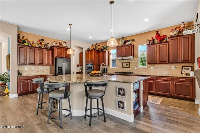 a kitchen with stainless steel appliances granite countertop a stove a sink dishwasher a refrigerator and a dining table with wooden floor