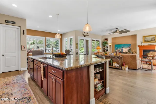 a kitchen with stainless steel appliances granite countertop a stove a sink dishwasher and a flat tv screen