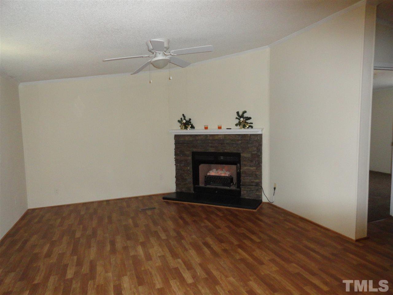 3388 Dirgie Mine Road Roxboro, NC 27574 - Photo 9 of 12 a view of an empty room with wooden floor a fireplace