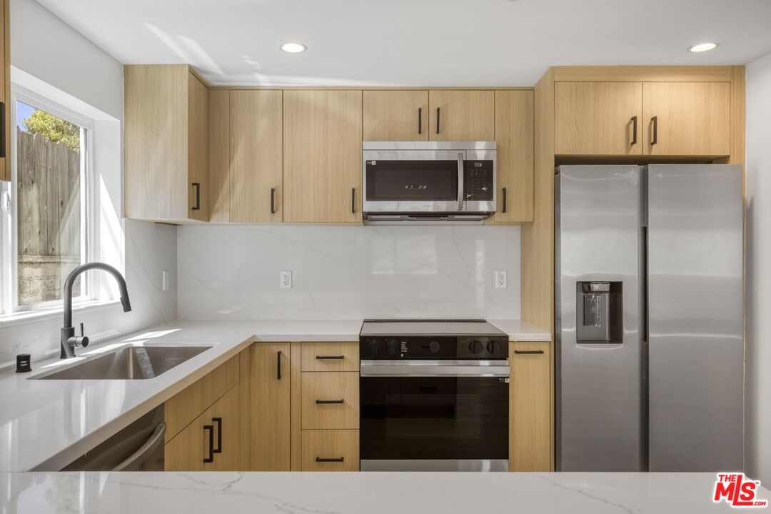 10826 3/4 Hesby Street North Hollywood, CA 91601 - Photo 11 of 26 a kitchen with stainless steel appliances wooden cabinets a sink and a stove