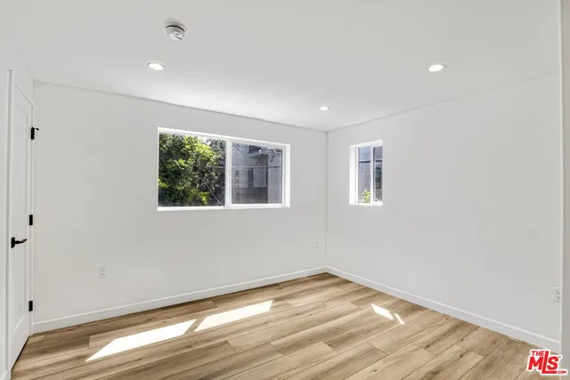 a view of empty room with wooden floor and fan