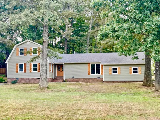 a front view of house with yard and trees in the background