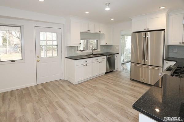 5 Gilbert Road Great Neck, NY 11024 - Photo 8 of 20 a kitchen with granite countertop a refrigerator a sink dishwasher a stove and white cabinets with wooden floor