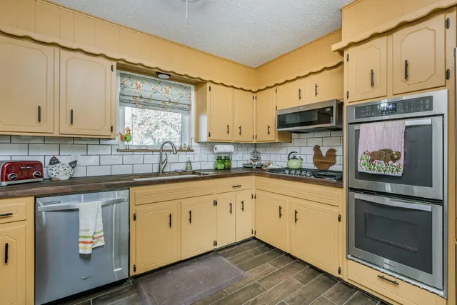 a kitchen with granite countertop a stove a sink and white cabinets with wooden floor