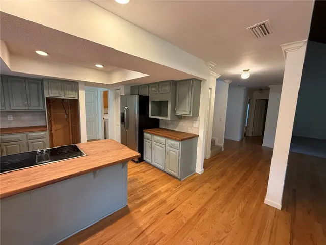a large kitchen with stainless steel appliances a large counter top and wooden floor