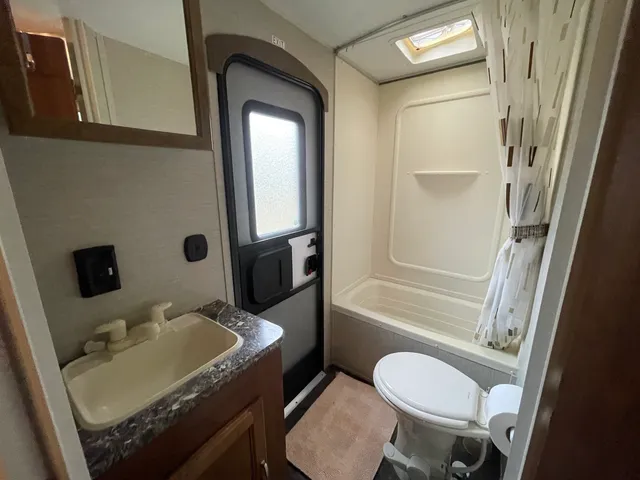 a bathroom with a granite countertop sink toilet a mirror and shower