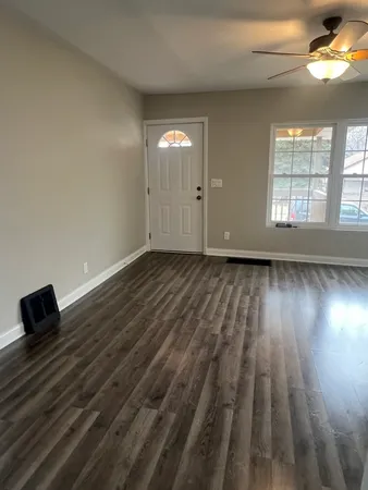 an empty room with wooden floor and windows
