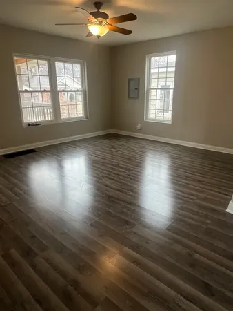 an empty room with wooden floor and windows