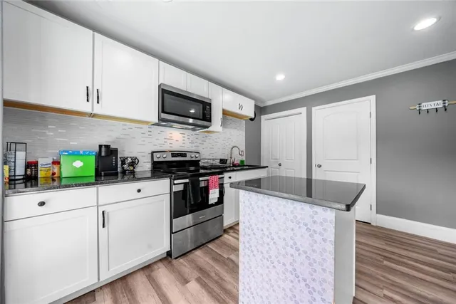 a kitchen with granite countertop a sink stainless steel appliances and white cabinets