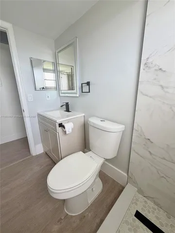 a white toilet sitting next to a bathroom sink and a mirror