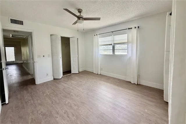 a view of empty room with wooden floor and fan