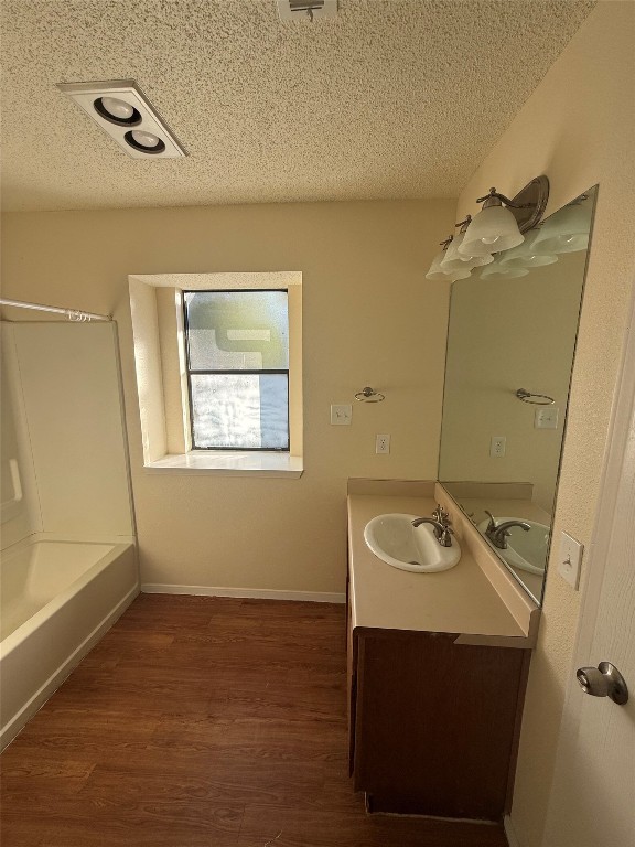 2504 Howellwood Way, Unit B Austin, TX 78748 - Photo 12 of 20 Bathroom with vanity, a textured ceiling, dark wood-style flooring, and tub / shower combination