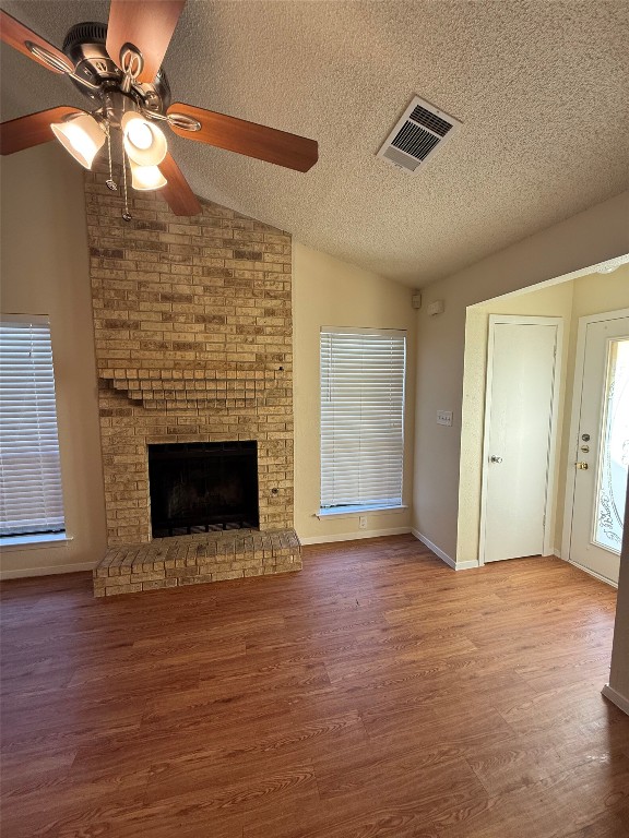 2504 Howellwood Way, Unit B Austin, TX 78748 - Photo 8 of 20 Unfurnished living room with lofted ceiling, a fireplace, a textured ceiling, a ceiling fan, and wood finished floors