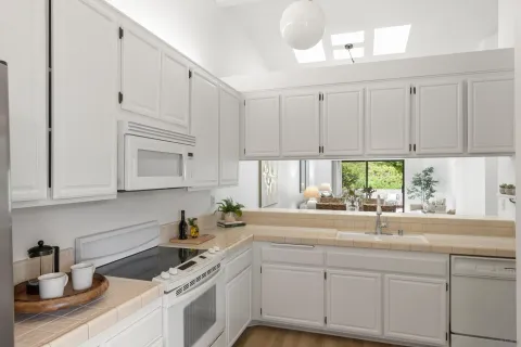 a kitchen with stainless steel appliances granite countertop white cabinets a sink and a window