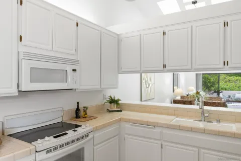 a kitchen with white cabinets and a window