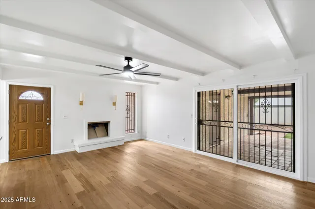 a view of a livingroom with wooden floor a ceiling fan and windows