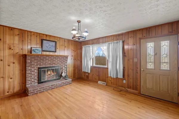 a view of an empty room with wooden floor fireplace and a window