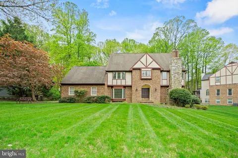 a view of a house with a big yard plants and large trees