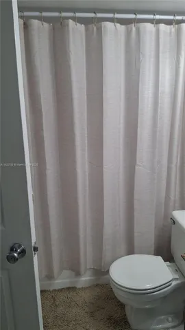 a white toilet sitting next to a shower curtain