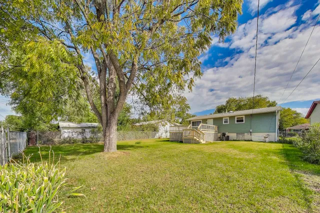 a view of a house with a big yard and large tree