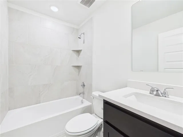 a bathroom with a granite countertop sink toilet a mirror and bathtub