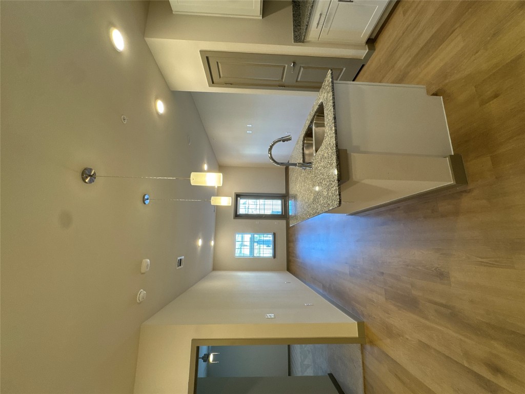 Kitchen featuring light stone countertops, decorative light fixtures, white cabinets, and recessed lighting