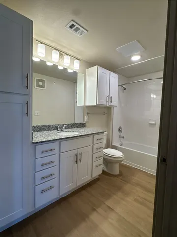 a bathroom with a granite countertop toilet a sink and a bathtub