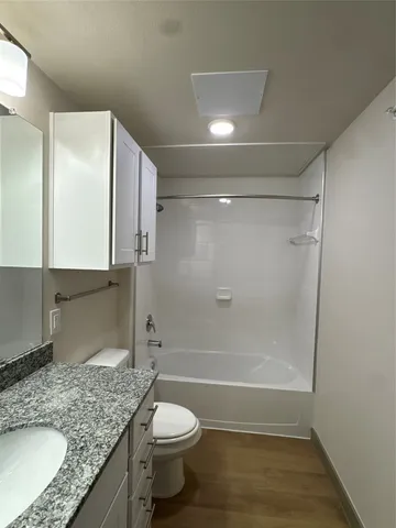 a bathroom with a granite countertop sink toilet and shower