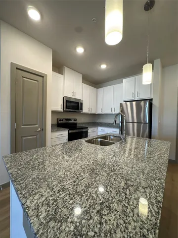 a kitchen with stainless steel appliances granite countertop a stove top oven a sink and a refrigerator
