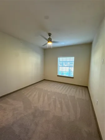 an empty room with a window and a ceiling fan