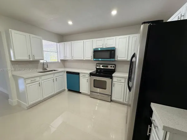 a kitchen with stainless steel appliances a stove a sink a refrigerator a microwave and cabinets