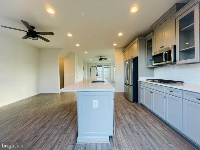 a large kitchen with stainless steel appliances granite countertop a lot of counter space and wooden floors