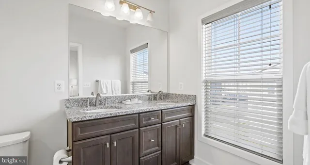 a bathroom with a granite countertop sink a toilet and a mirror