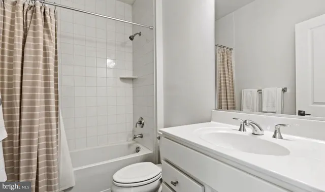 a bathroom with a granite countertop bathtub shower sink vanity mirror and toilet