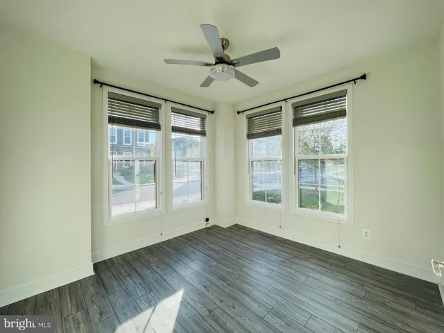 an empty room with wooden floor fan and windows