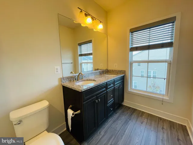 a bathroom with a granite countertop sink toilet and mirror