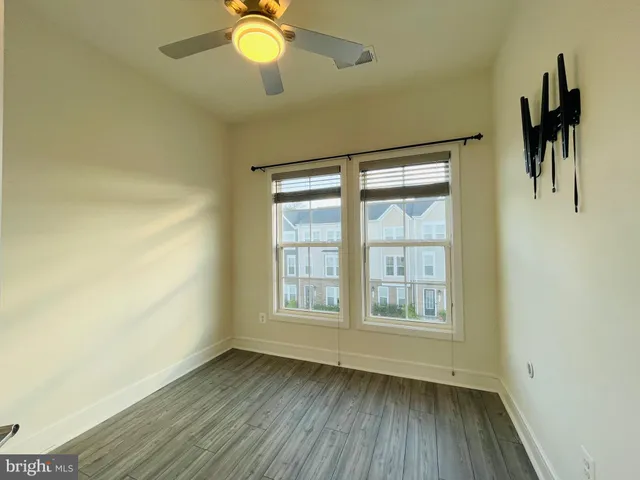 a view of an empty room with window and wooden floor